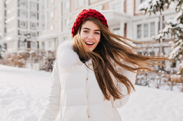 빨간 모자 눈 가득한 거리에 얼어 붙은 아침에 재미 놀된 행복 한 여자. 긍정, 진정한 쾌활한 감정 표현