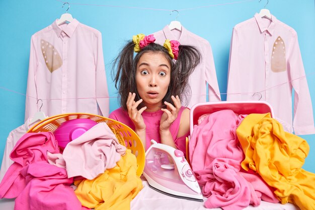astonished housewife reacts on terrifying news raises palms has much laundry to iron stares bugged eyes at