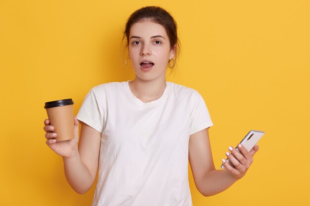 Astonished lady with opened mouth standing against yellow wall