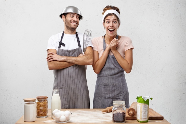 Astonished overjoyed female in apron looks with bugged eyes and excitement realizes that she prepared very delicious supper with help of husband