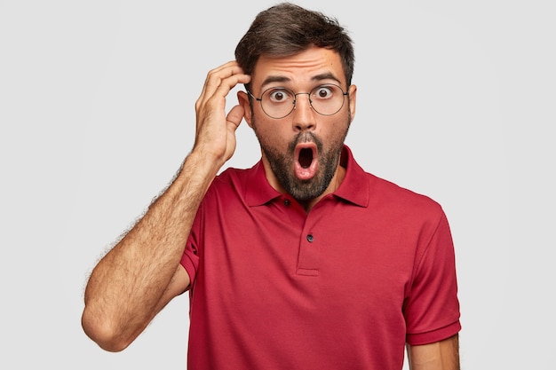 Astonished young emotional man posing against the white wall