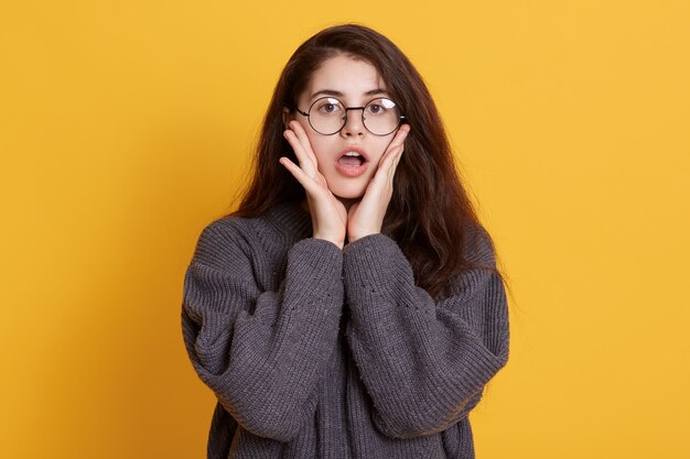 Astonished young woman dresses black sweater and spectacles