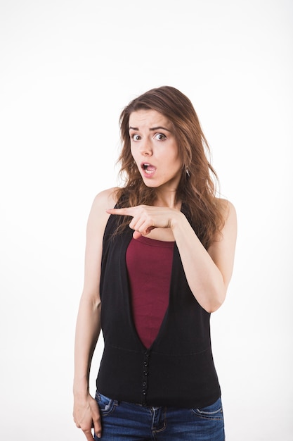 Astonished young woman pointing at something isolated on white backdrop