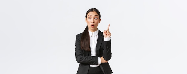 Изумленная умная азиатская женщина-предприниматель, менеджер по строительству, имеет отличный план, поднимая палец вверх, чтобы предложить решение, делиться мыслями и идеями с группой, стоящей на белом фоне