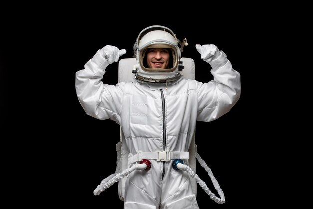 우주 비행사의 날 우주인은 웃고 있는 열린 유리 헬멧을 주먹으로 들고 우주 공간에서 흥분했습니다.