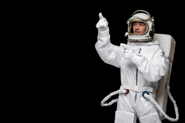 Free photo astronaut day spaceman in galaxy black background space suit helmet pointing direction with finger