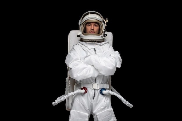 Бесплатное фото Космонавт дня космонавта в космическом шлеме скафандра скрестил руки, стоя на месте в галактике