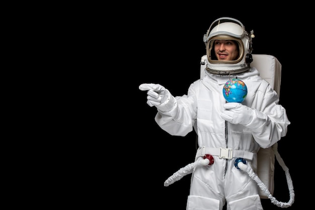 Foto gratuita astronauta astronauta in tuta spaziale casco di vetro che tiene globus e sorridente dito puntato