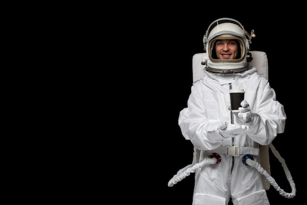 Free photo astronaut day spaceman in white space suit smiling open glass helmet holding black cup