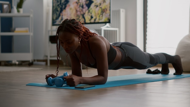 Athlete african in sportwear doing fitness exercices putting cronometer on phone