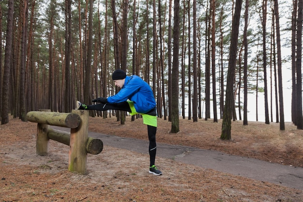 Athlete stretching leg in forest