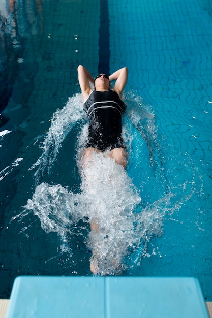 Athlete swimming in pool full shot