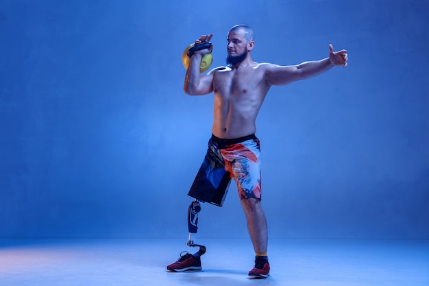 Foto gratuita atleta con disabilità o amputato isolato sulla parete blu dello studio