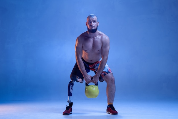 Athlete with disabilities or amputee isolated on blue studio wall