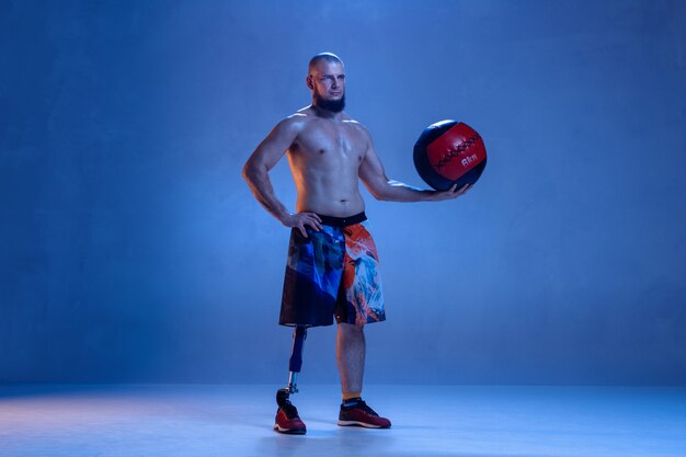 Спортсмен-инвалид или человек с ампутированной конечностью, изолированные на синей стене студии