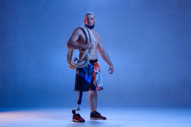 Спортсмен-инвалид или человек с ампутированной конечностью, изолированные на синей стене студии