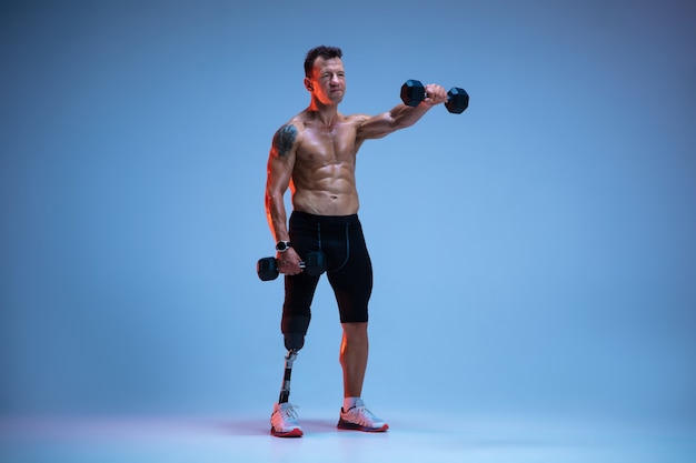 Free photo athlete with disabilities or amputee isolated on blue  wall professional male sportsman