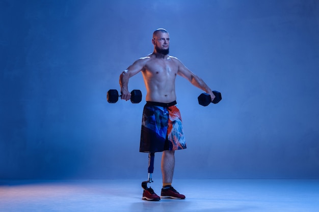 Athlete with disabilities or amputee isolated on blue wall.