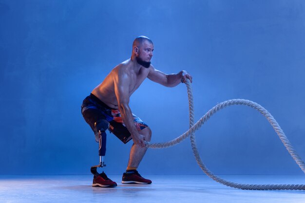 Athlete with disabilities or amputee isolated on blue wall.