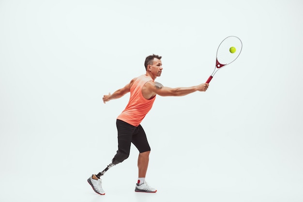 Athlete with disabilities or amputee isolated on white. Professional male tennis player with leg prosthesis training