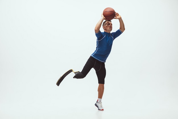 Free photo athlete with disabilities or amputee isolated on white studio space. professional male basketball player with leg prosthesis training and practicing in studio.