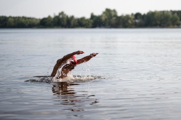 Athlete with red cap swimming in lake
