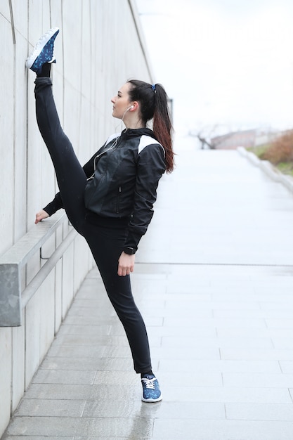 通りでストレッチを行うアスリート女性