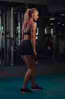 Free photo athletic blonde woman in sportswear doing exercise on the triceps on the crossover machine in the gym.
