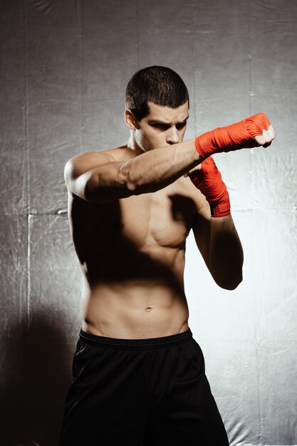 Athletic boxer punching with determination and precaution over silver kground