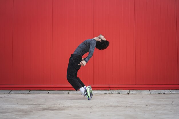 Athletic cool European guy posing outdoors in front of a red wall