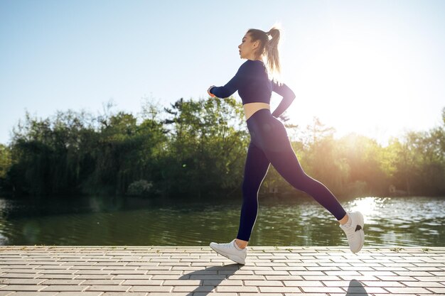 Athletic fit young woman jogging early in the morning in park