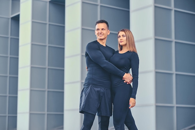 The athletic fitness couple modern building background.