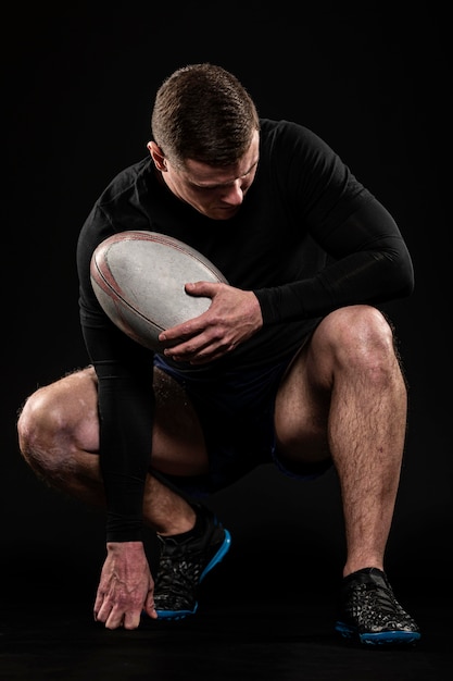 Athletic handsome rugby player holding ball while posing