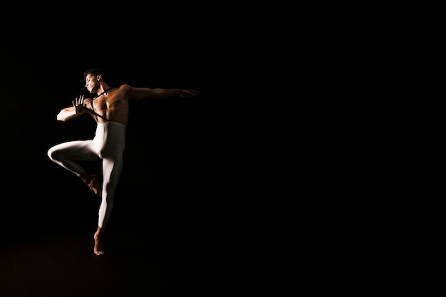 Athletic male dancer dancing on black background 