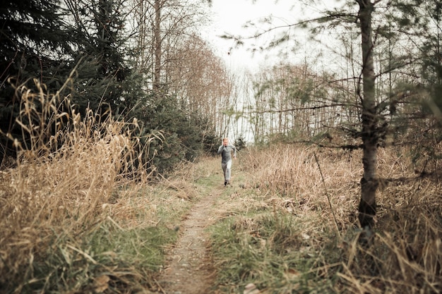 森林トレイルで走っている運動男性