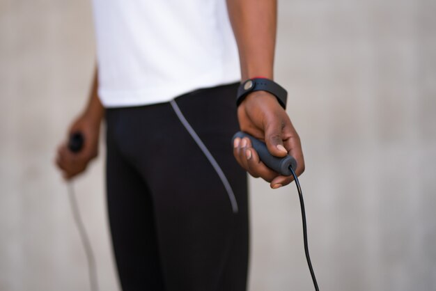 Athletic man doing exercise and jumping the rope outdoors