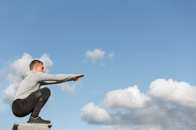 Athletic man doing squats with copy space