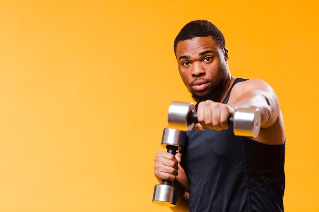 Athletic man exercising with weights and copy space