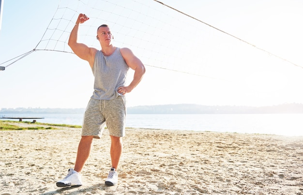 A athletic man looking at seaside on wild sand beach.