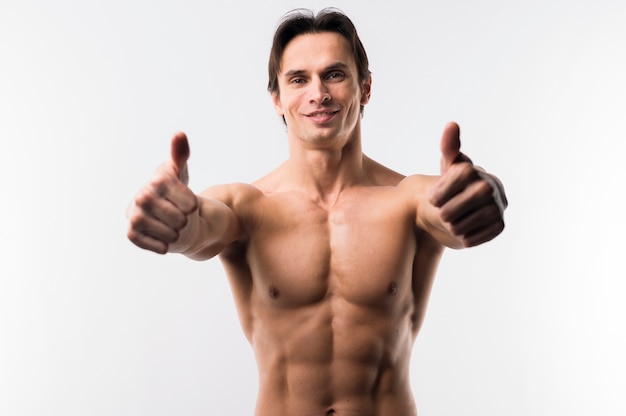 Athletic man posing shirtless and giving thumbs up