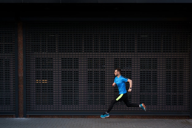 Free photo athletic man running at urban street against grey background