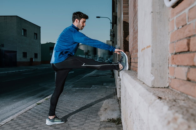 Foto gratuita uomo atletico di riscaldamento sulla strada