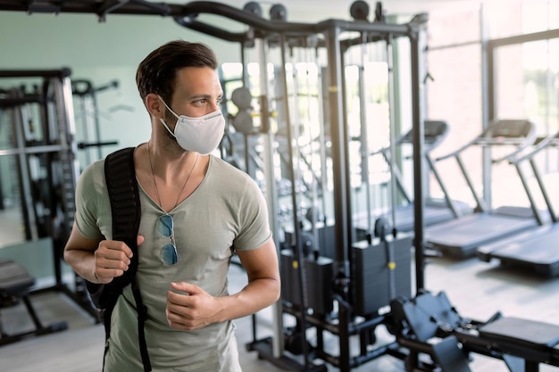 Athletic man wearing protective face mask in a gym