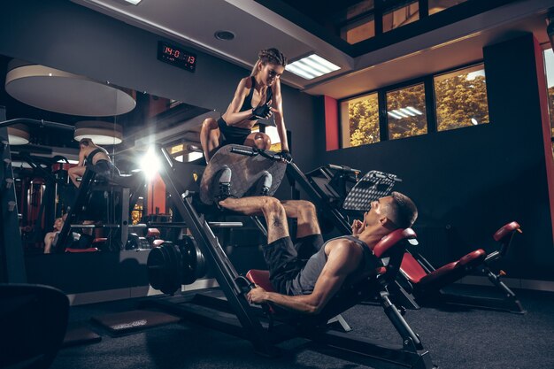 Athletic man and woman with a dumbbells training and practicing in gym.