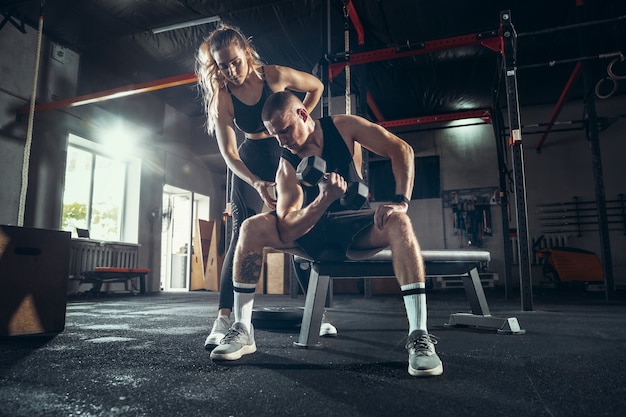 Athletic man and woman with dumbbells