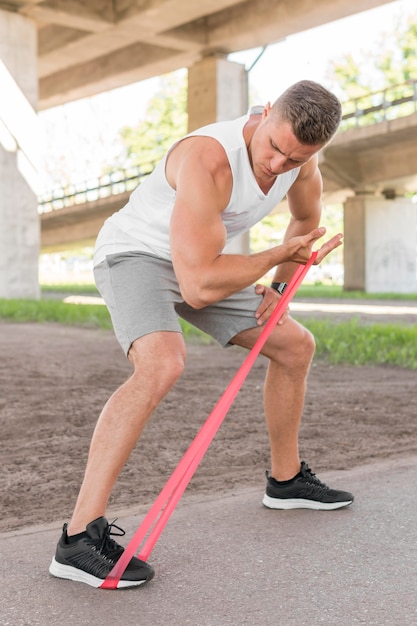 赤のストレッチバンドでワークアウト運動の男