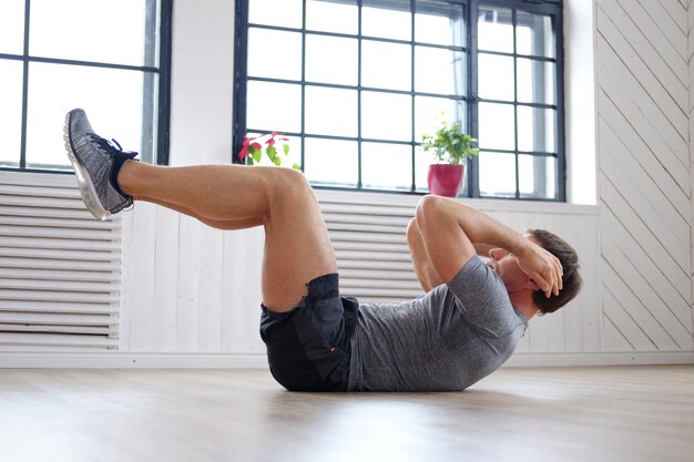 Athletic middle age man doing stomach workouts at home.