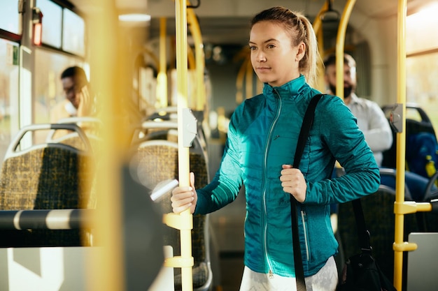 Athletic woman commuting to sports training by bus