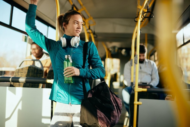 Athletic woman commuting to sports training by bus