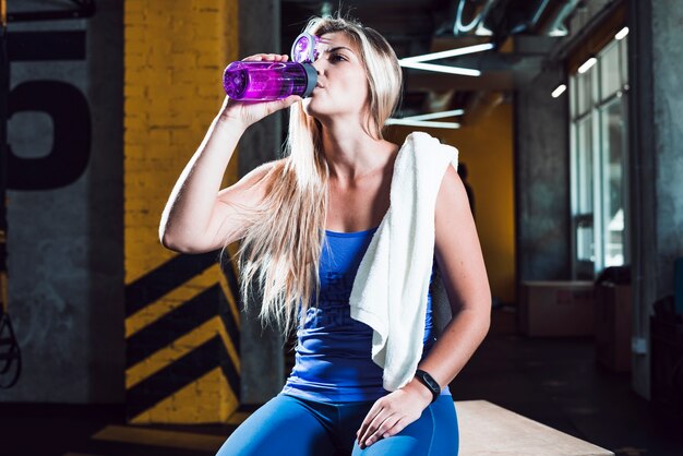 An athletic woman drinking water in gym